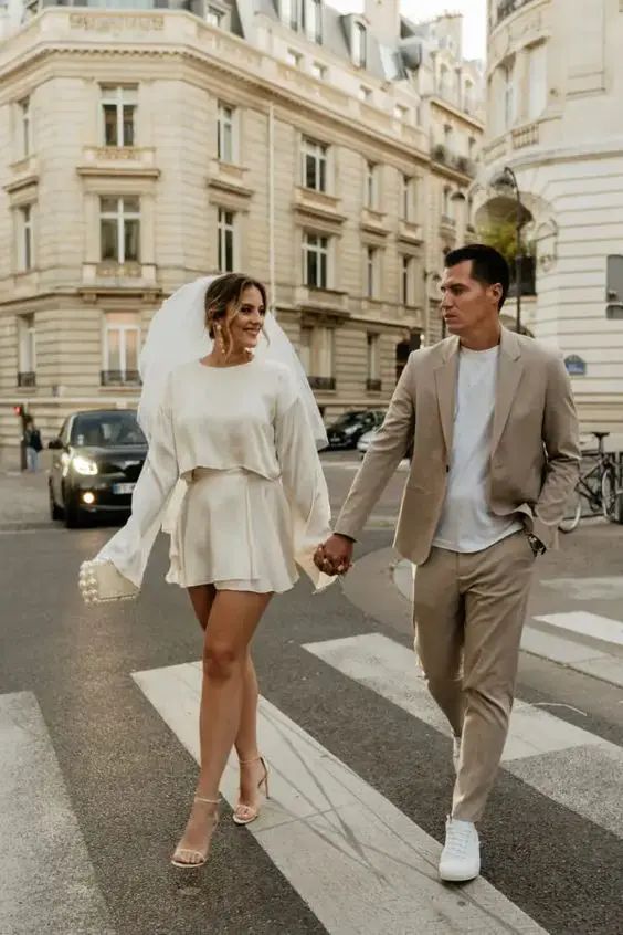 a man and woman walking across a street holding hands