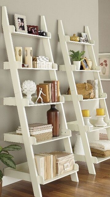 three white ladder bookshelves in a living room