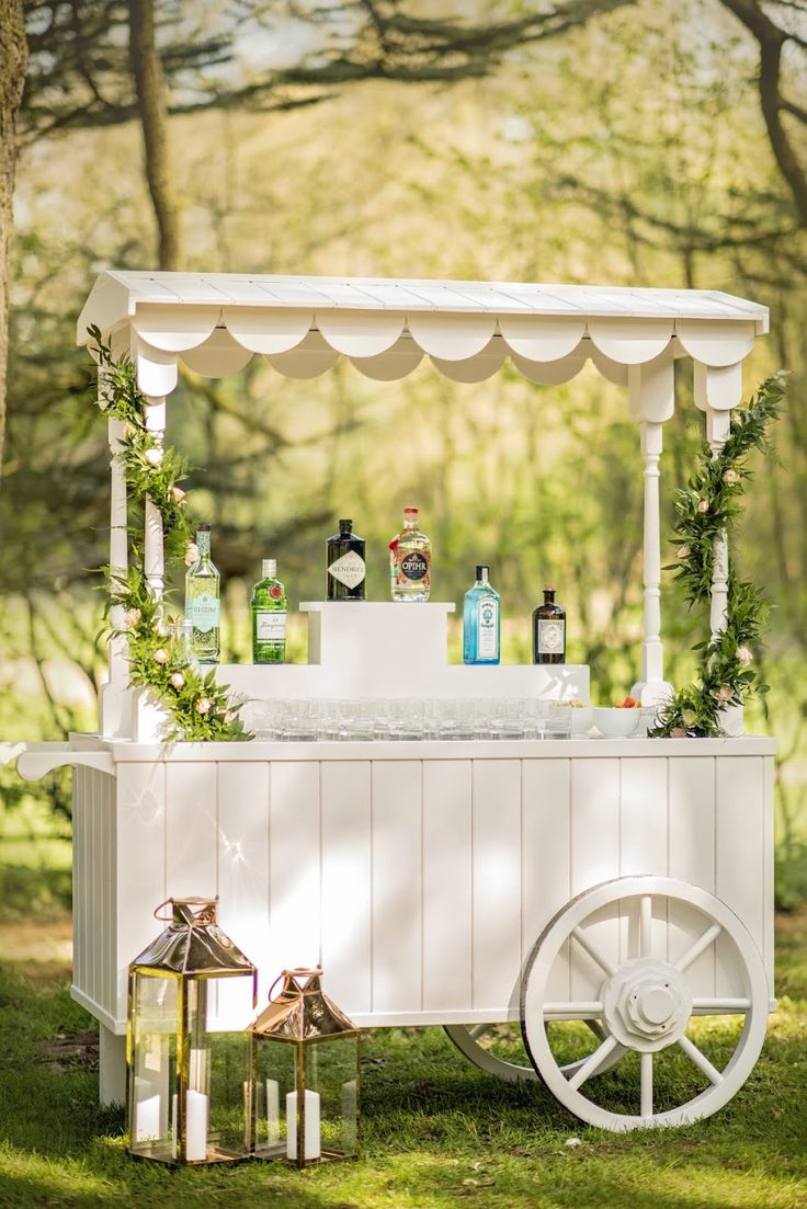 an outdoor bar with bottles and candles on the top is set up in the grass