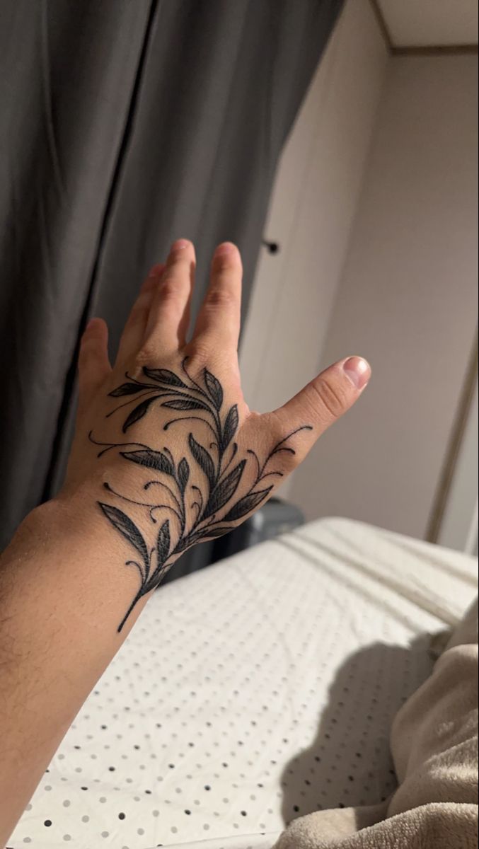 a person's hand with a tattoo on it, in front of a bed