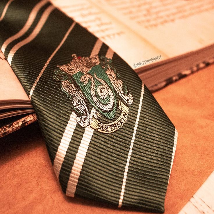 a green striped tie sitting on top of a table next to an open book and pen