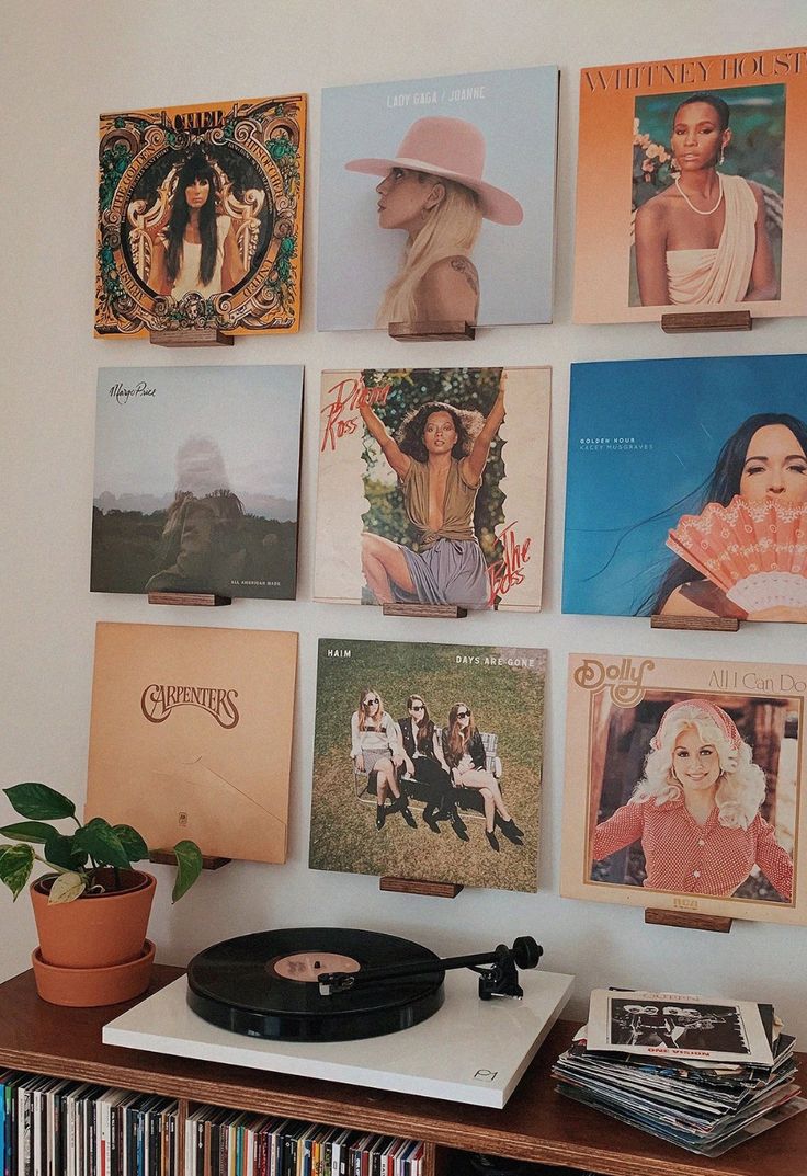 a record player sitting on top of a wooden table next to a wall covered in records