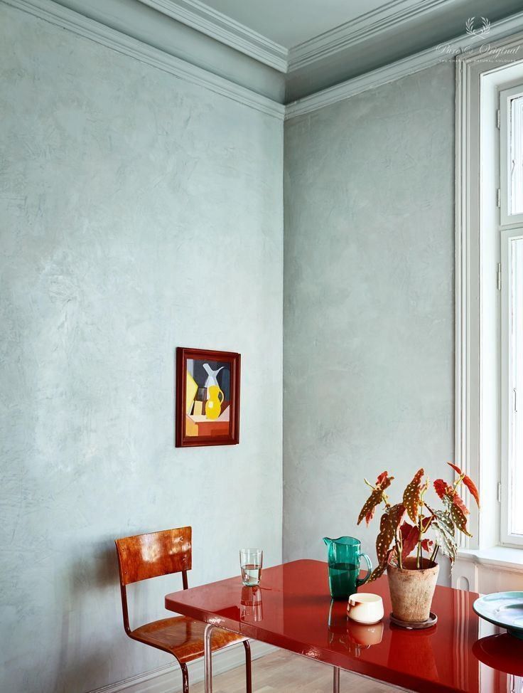 a red table with two chairs next to it and a potted plant on top