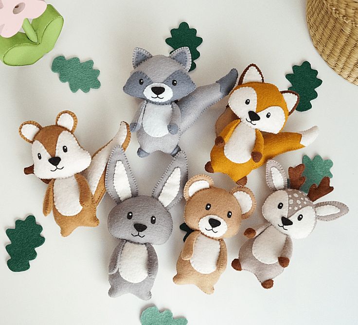 a group of stuffed animals sitting next to each other on a white table with green leaves