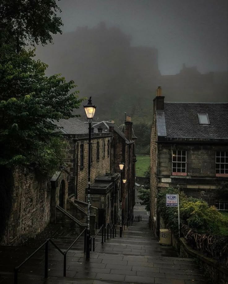 an alley way in the middle of town with fog on the ground and buildings around it