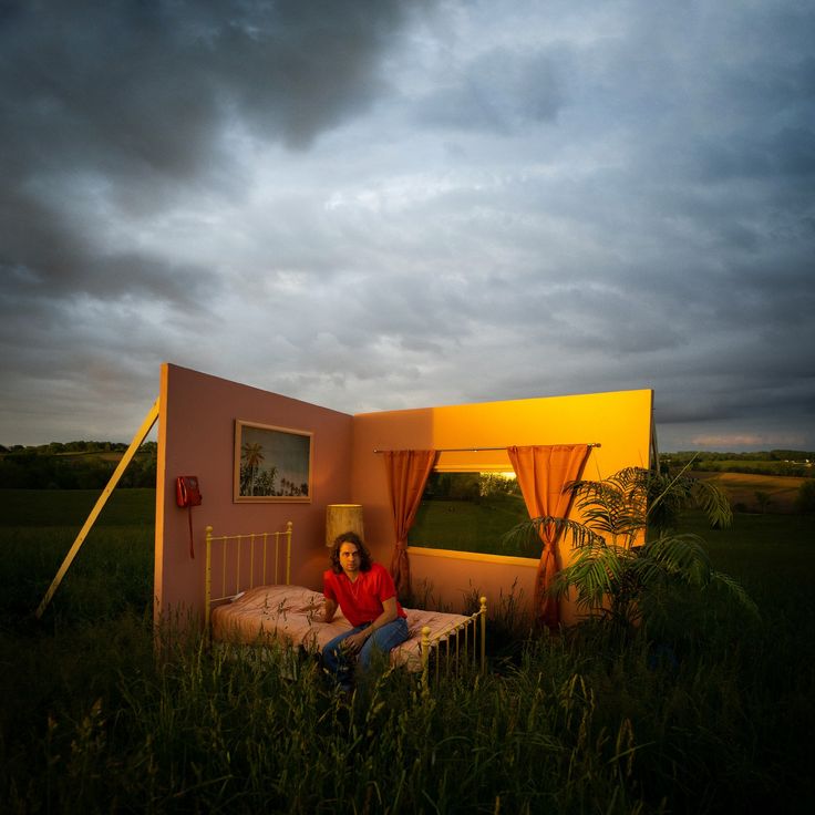 a woman sitting on top of a bed in the middle of a field