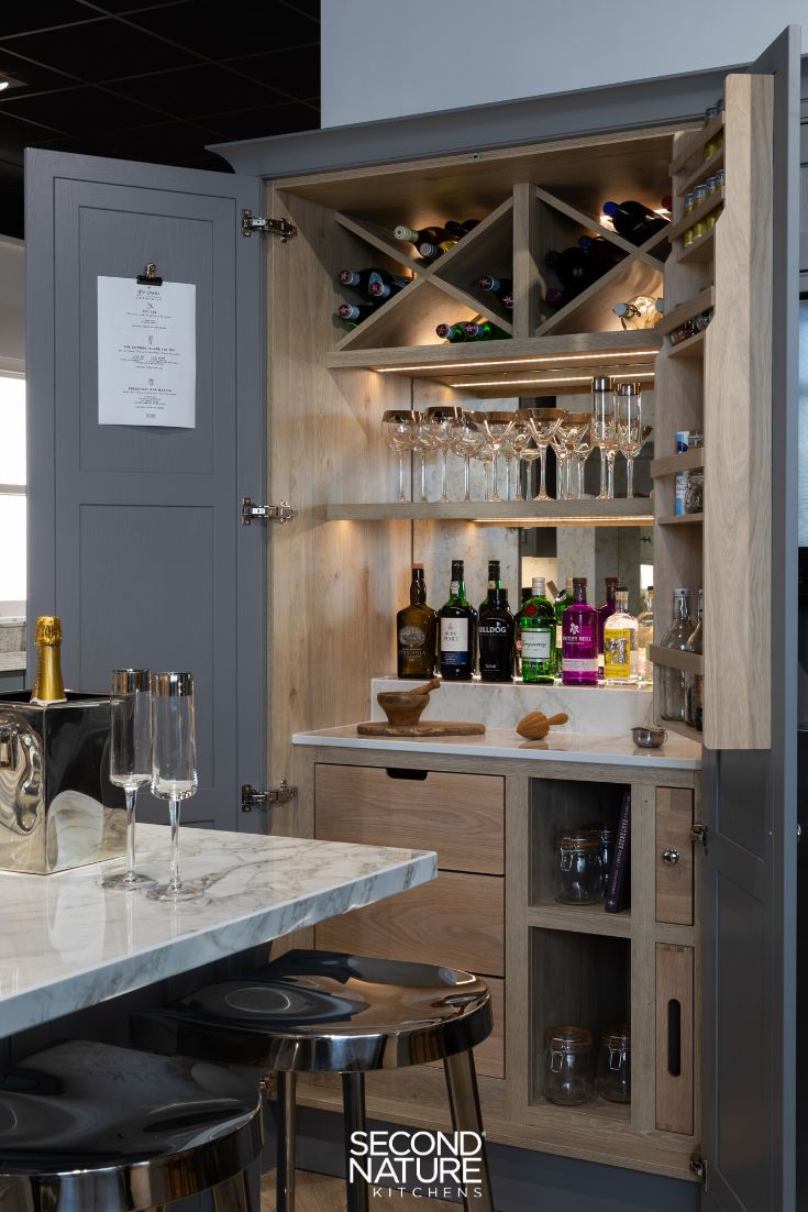 a kitchen with wine glasses and bottles on the counter top, next to an open cabinet