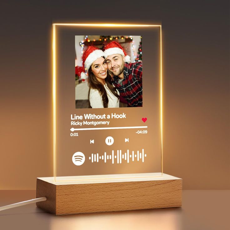 a light up photo frame with a christmas theme on the front and an image of a man and woman in santa's hats