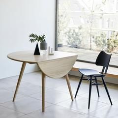 two chairs and a table in front of a window with a plant on the side