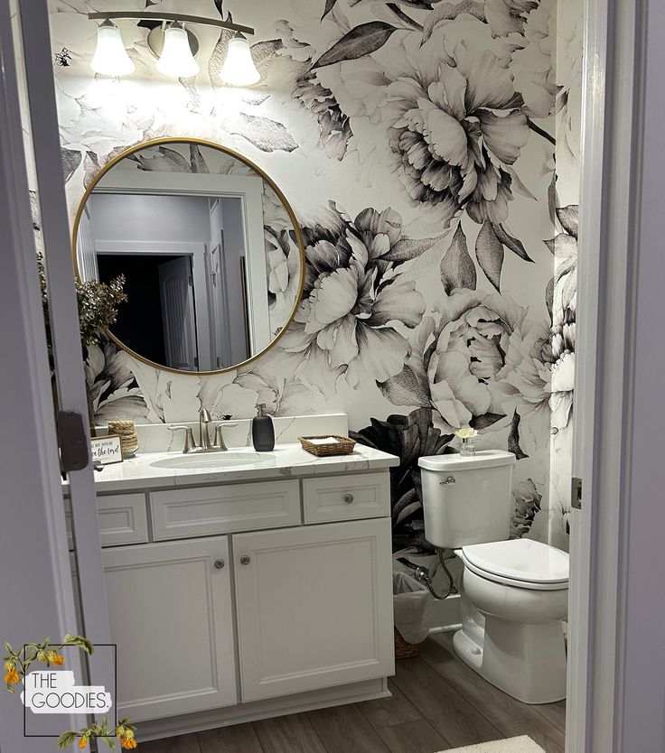 a bathroom with floral wallpaper and white vanity, toilet and sink area in it