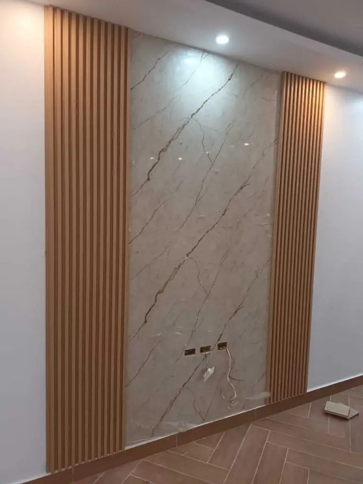 an empty room with marble walls and wood trimmings on the wall, along with wooden flooring