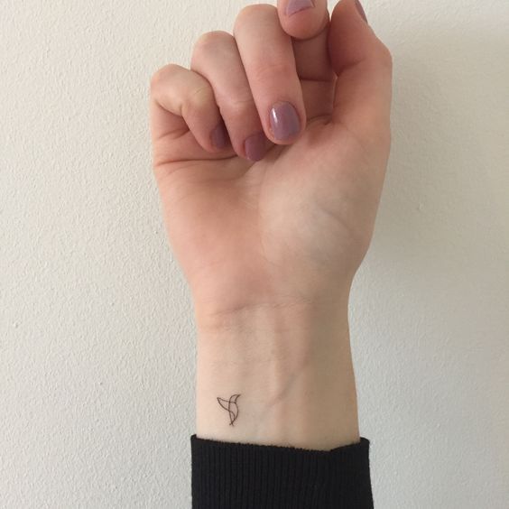 a woman's hand with a small tattoo on her left wrist and the other arm