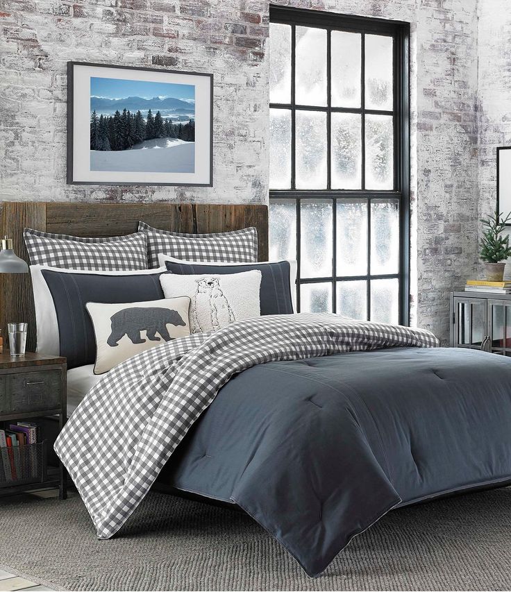 a bed with black and white comforters in front of a brick wall next to a window