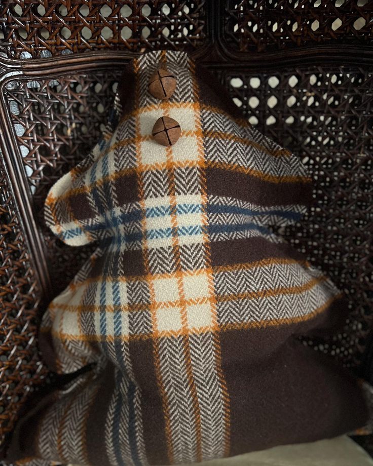 a brown and white checkered blanket sitting on top of a wooden chair next to a pillow