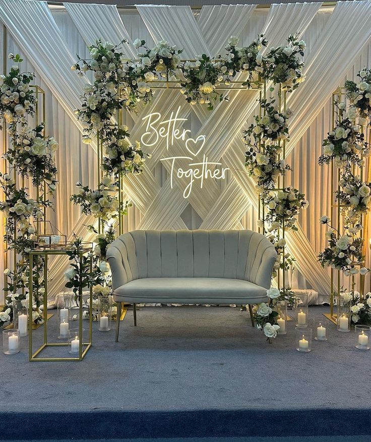 a couch sitting under a wedding arch decorated with flowers and candles