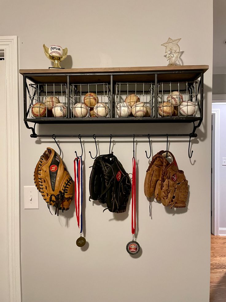 a wall mounted shelf filled with baseballs and mitts hanging from it's sides