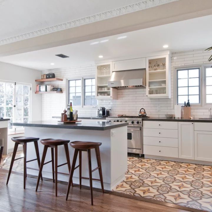 an open kitchen and dining room with white cabinets, wood floors, and tile flooring