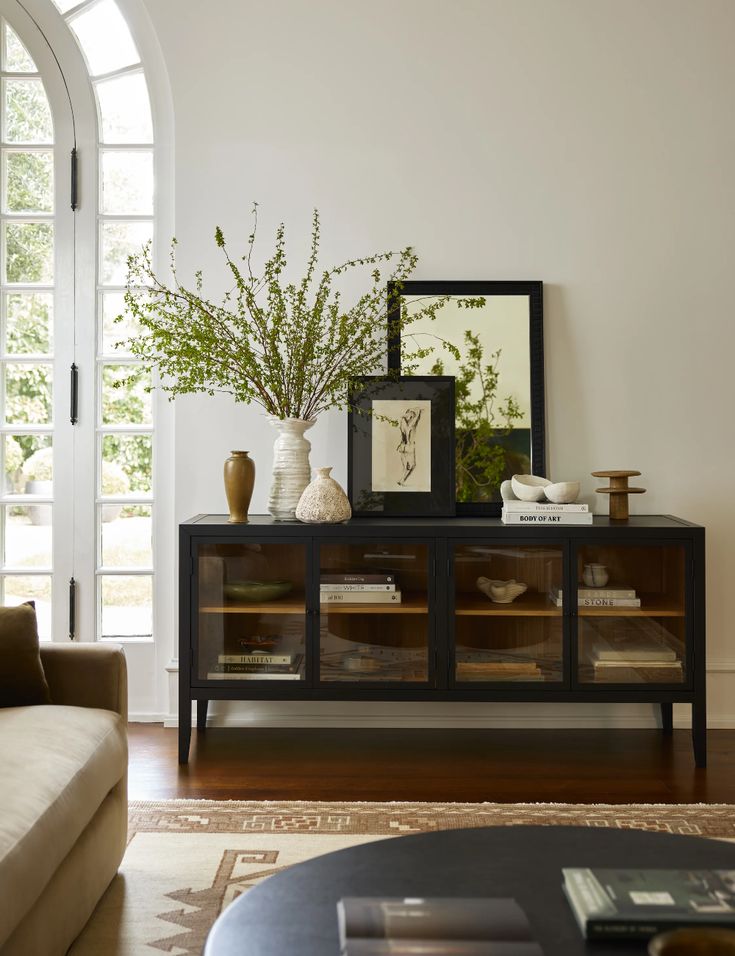 a living room with a couch, coffee table and vases on top of it