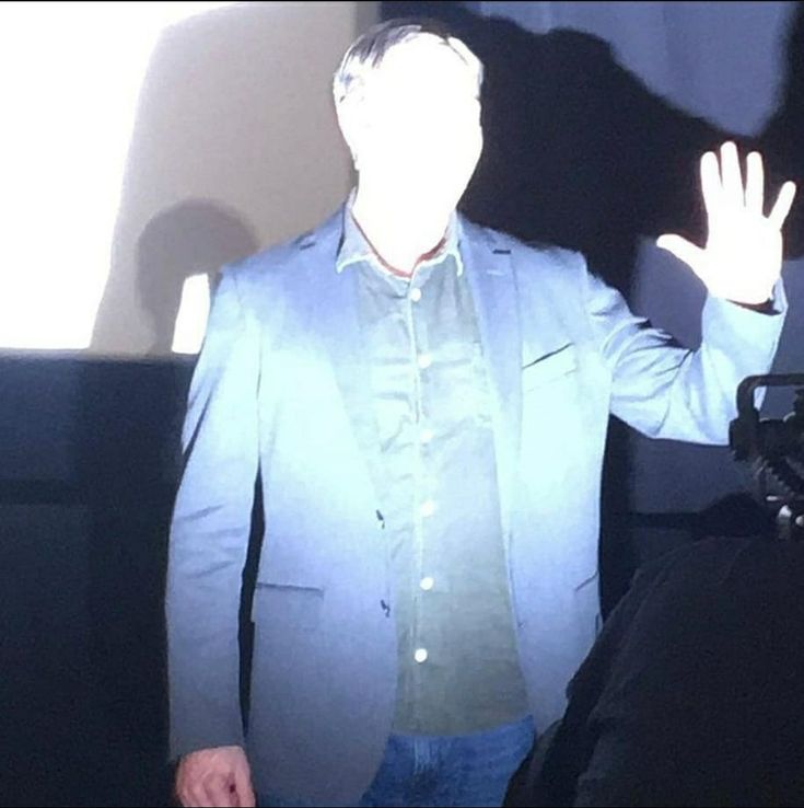 a man standing in front of a projector screen with his hands up to the side