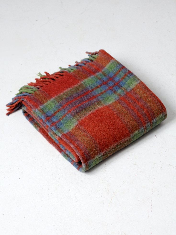 a red and green plaid blanket laying on top of a white table