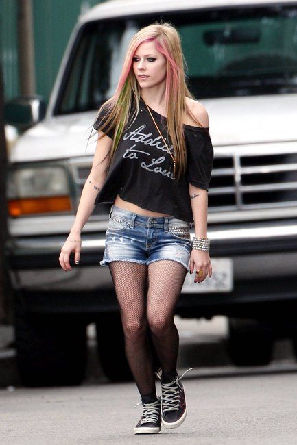 a woman with pink hair walking down the street in short shorts and black t - shirt