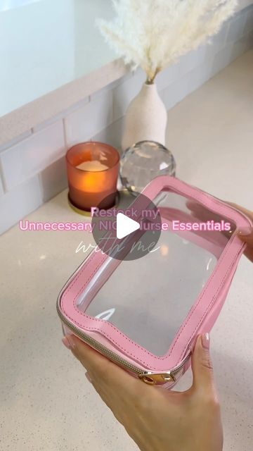 a person holding a pink case in front of a white counter top with flowers and candles