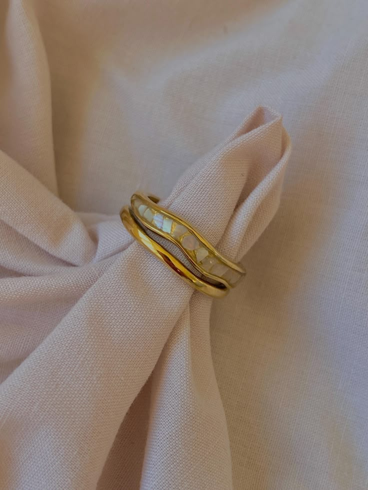 two gold rings sitting on top of a white cloth