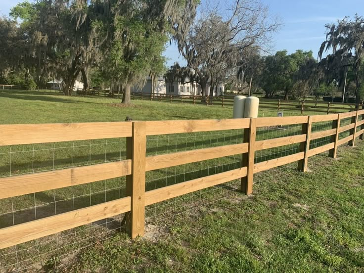 a wooden fence in the middle of a grassy field