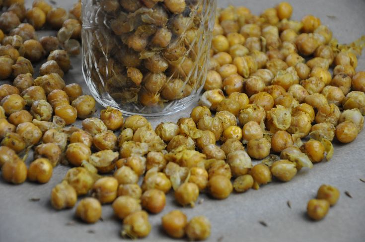 a pile of chickpeas sitting on top of a table next to a glass container