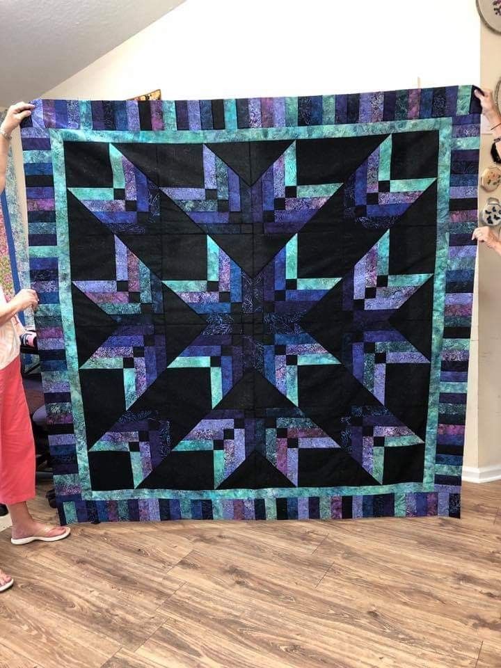 a woman standing next to a large quilt