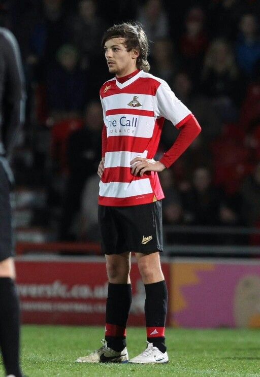 a man standing on top of a soccer field wearing a red and white striped shirt