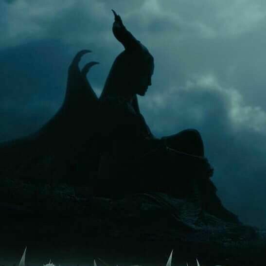 the silhouette of a demon sitting on top of a hill