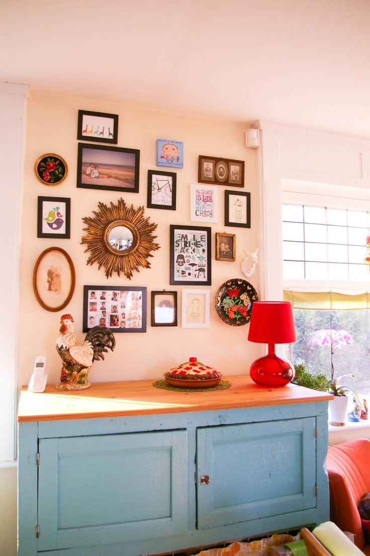 a room with many pictures on the wall and a red lamp in front of it