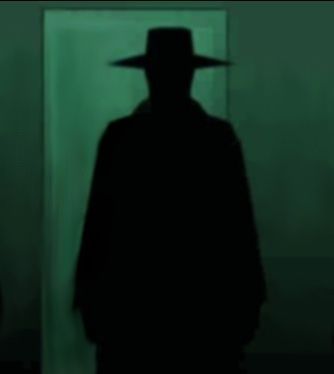 the shadow of a man wearing a hat in front of a green wall with a mirror