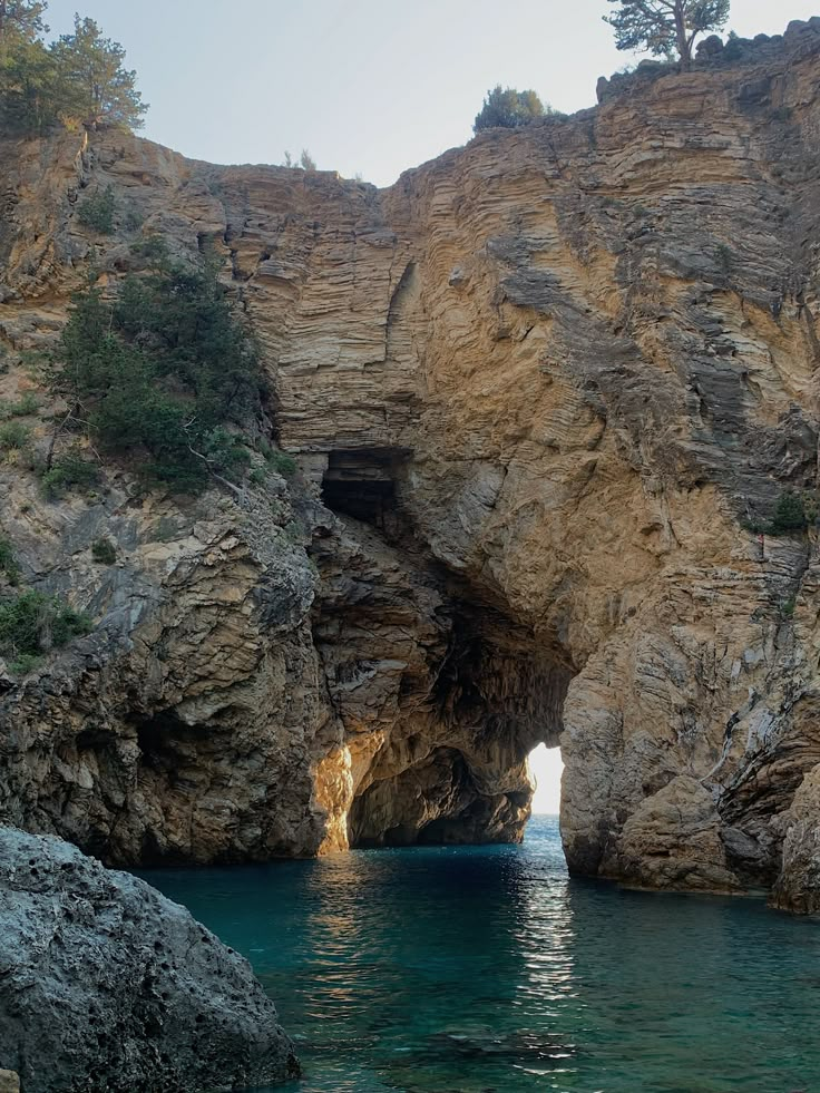 the water is crystal blue and clear in this photo, as seen from inside a cave