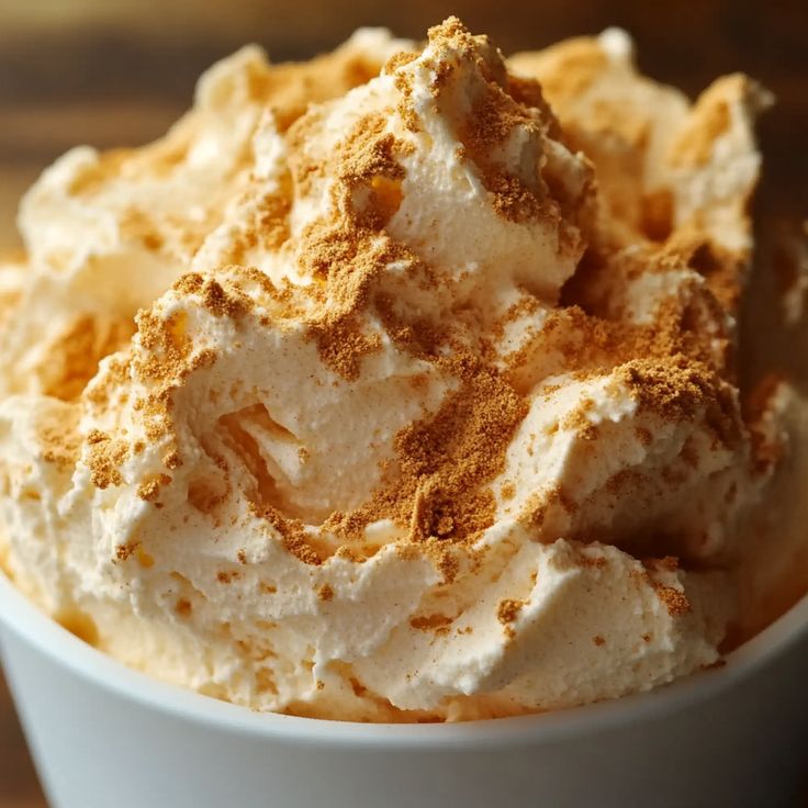 a white bowl filled with whipped cream on top of a wooden table