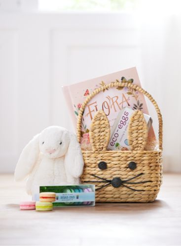 a stuffed bunny sitting next to a basket filled with books