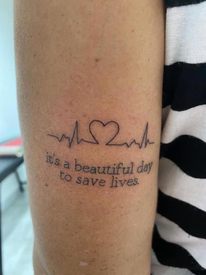 a woman with a tattoo on her arm saying it's a beautiful day to save lives