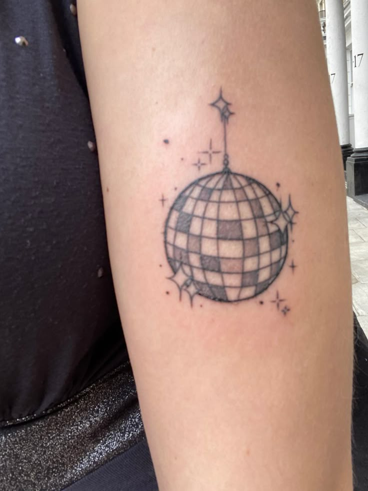 a person with a tattoo on their arm that has a globe and stars around it