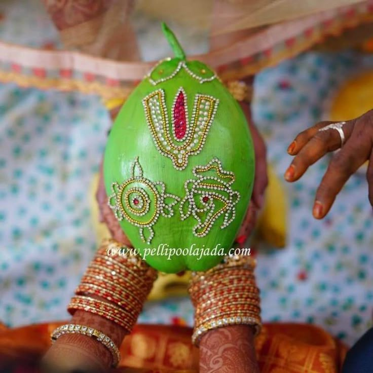 a woman's hands holding a green decorated egg