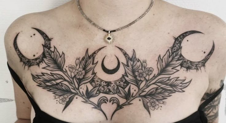 a woman with tattoos on her chest is wearing a black dress and has two crescents