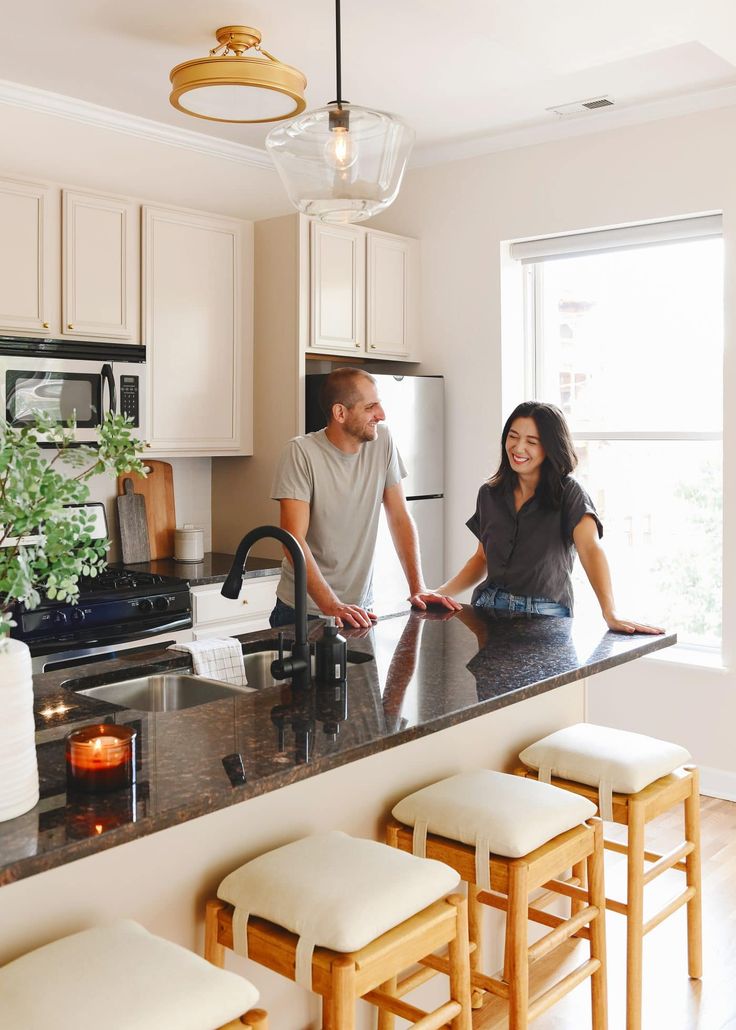 a man and woman standing at the kitchen counter