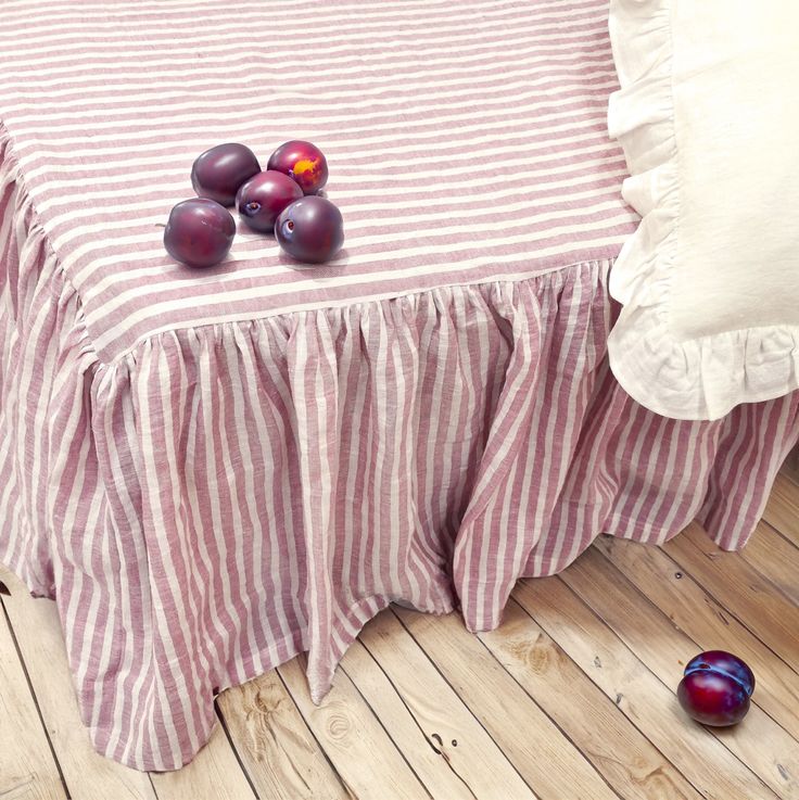 some plums are laying on a striped bed skirt