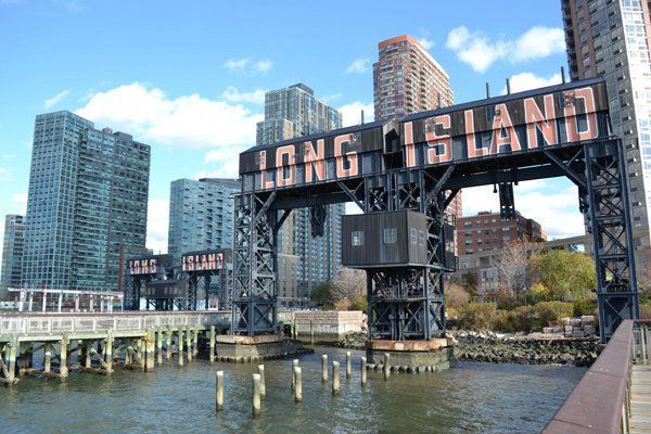 a bridge that has the word long island on it over water with buildings in the background