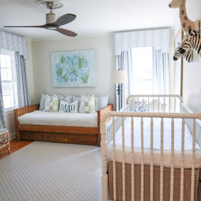 a baby's room with a bed, crib, and zebra head on the wall