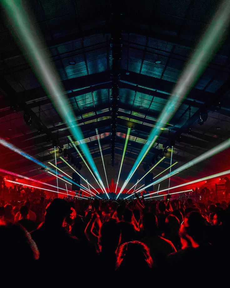 a large group of people in a dark room with bright lights on the ceiling and floor