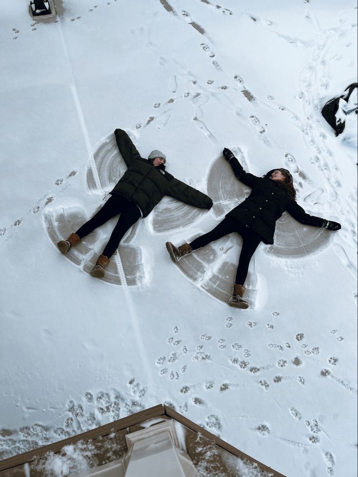 two people laying down in the snow with their feet on each other's legs