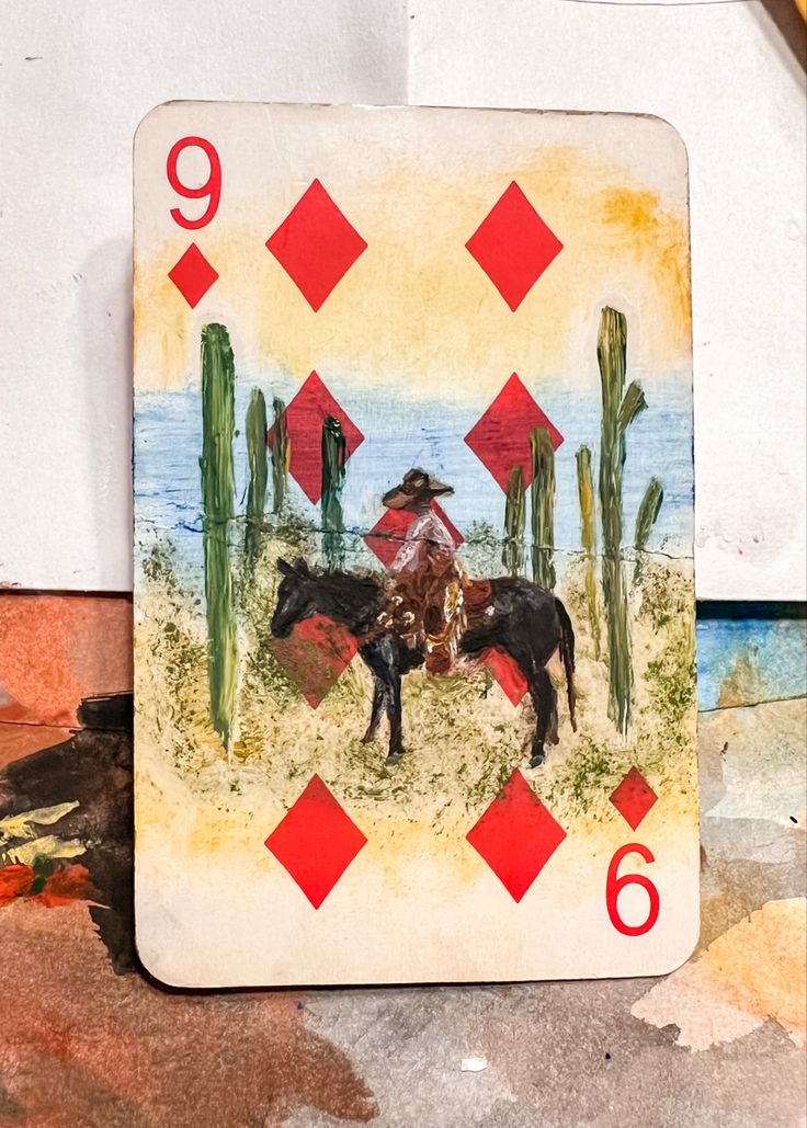 a playing card with an image of a man on a horse in the desert surrounded by cacti