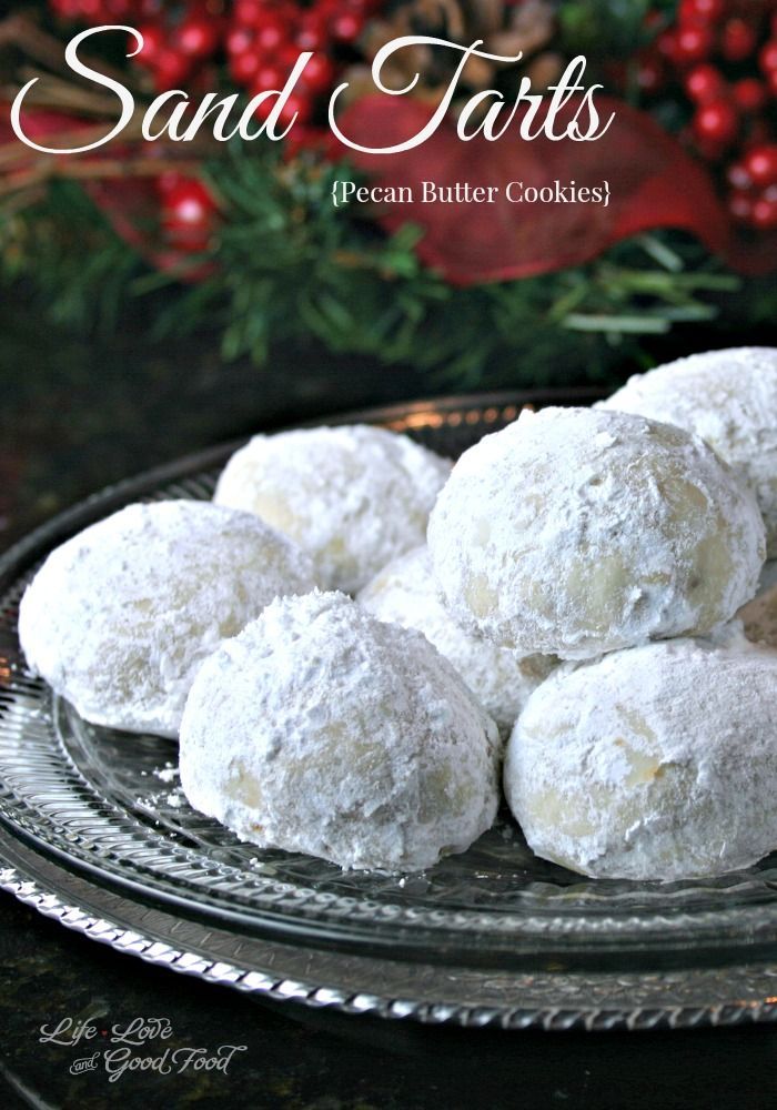 snowball cookies on a glass plate with holly wreath in the background and text overlay that reads sand tarts pecan butter cookies