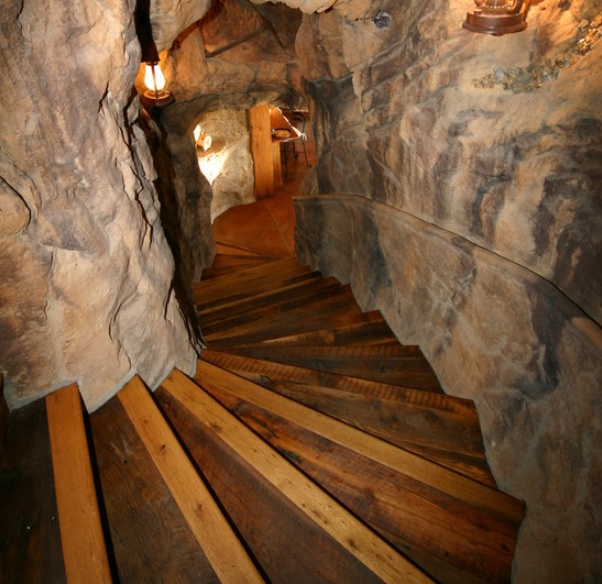 a long wooden staircase leading up to a cave like area with lights on it's sides